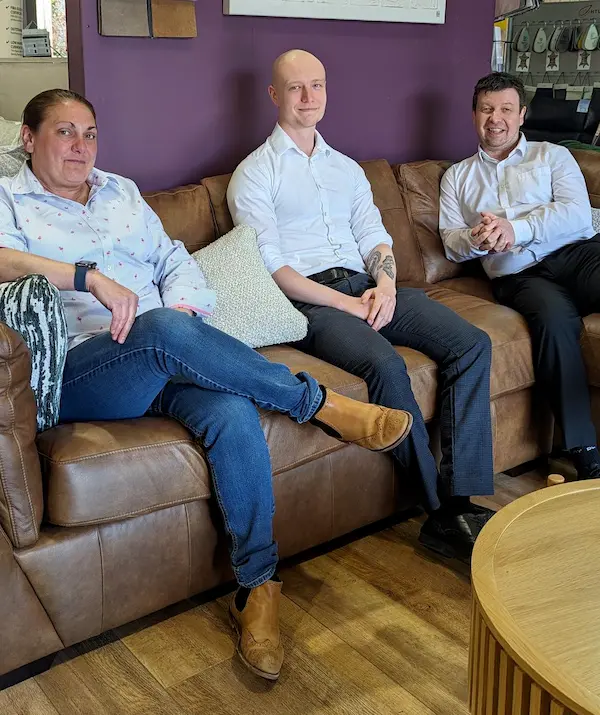 Three people sitting on a brown leather sofa